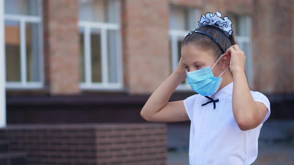 Outdoors Portrait of Schoolgirl, Teenage Girl, Wearing a Medical Protective Mask, on the Background