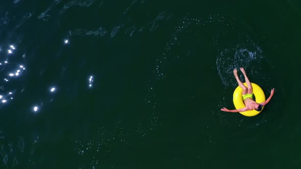 Boy with inflatable swim ring, Top down view of boy swimming with rubber ring
