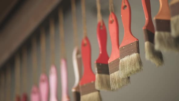 Many Orange Red Pink Color Brushes Hang on Ropes From Ceiling