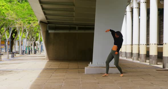 Female dancer dancing under a bridge in the city 4k