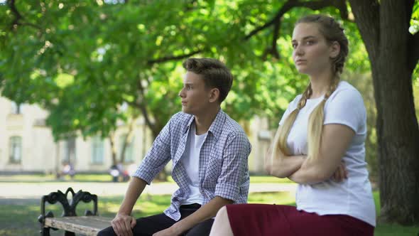 Offended Teen Couple Sitting in Park on Bench, Ignoring Each Other, Conflict