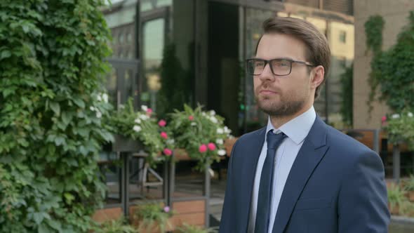 Serious Businessman Walking in Street, Side View