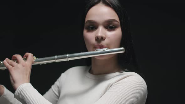 Caucasian Beautiful Young Woman Brings Flute to Her Lips and Plays Music Confident Look Front View