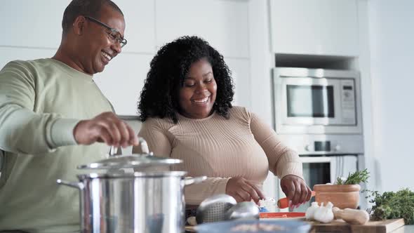 Happy Afro Latin father and daughter preparing lunch together in modern house kitchen