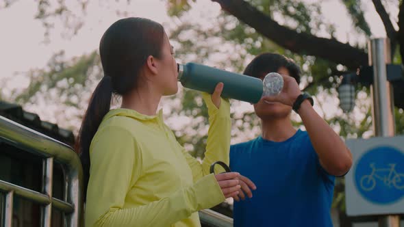 Couple sports runner drinking water after the run outdoors.