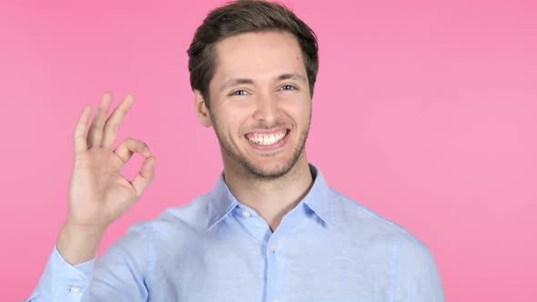 Gesture of Okay By Young Man on Pink Background