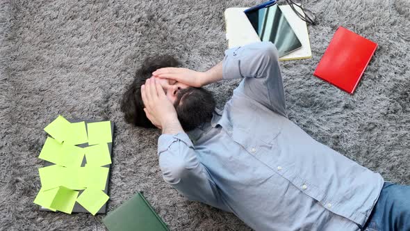 Young Man Surrounded By Computer and Documents Very Tired and Exhausted