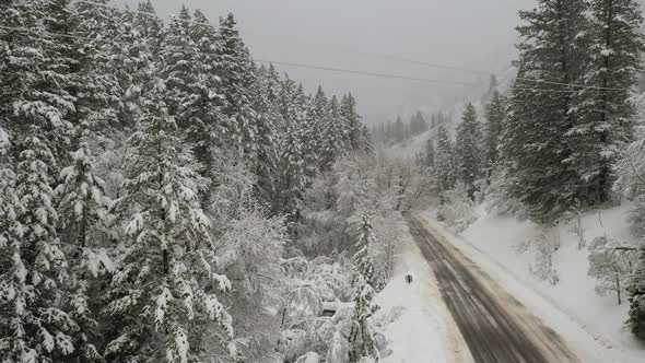 Flying through snowy canyon as truck drives down road