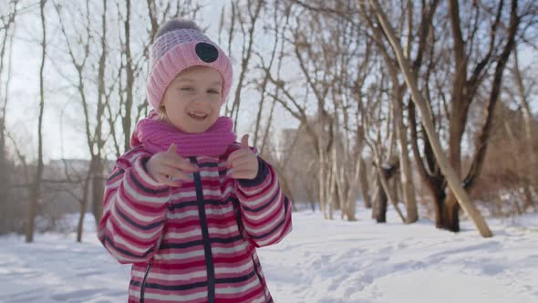 Smiling Child Kid Showing Ok Sign Smiling Dancing Thumbs Up on Snowy Road in Sunny Winter Park