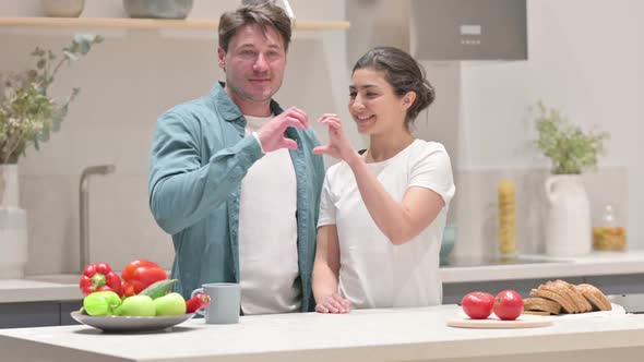 Mixed Race Couple Making Heart Shape By Hands While in Kitchen