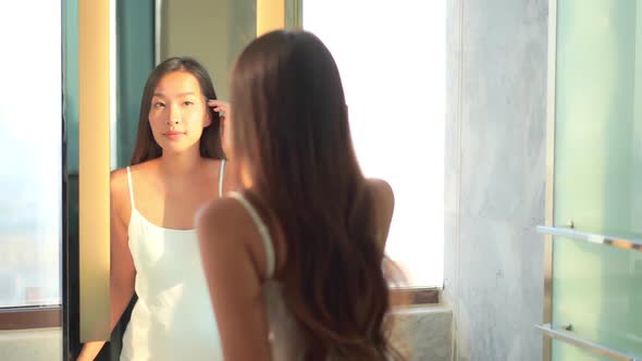 Young asian woman check her face on mirror