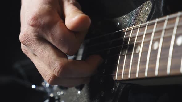 Close Up Fingers of Guitarist Strumming the Strings. Hand of Male Musician Playing on Electric