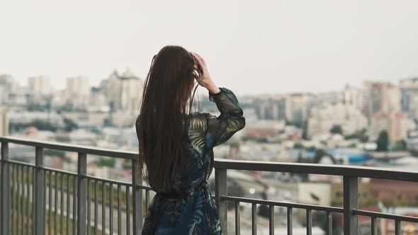 Graceful Lady Adjusts Waving Hair on Viewing Deck in City