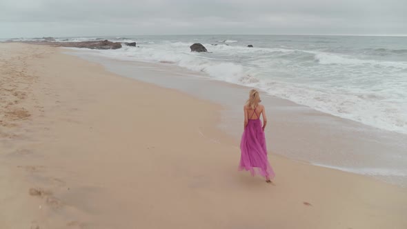 Woman In A Dress Wandering On The Beach