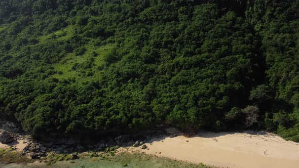 Aerial zoom in on green cliff in Nunggalan beach