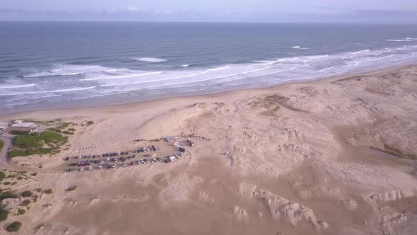 Aerial tilting up seascape shot of Birubi Beach sand dunes desert and camel rides attraction at Stoc