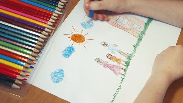 A Child's Hand Draws Blue Clouds Above the Family Next to the House