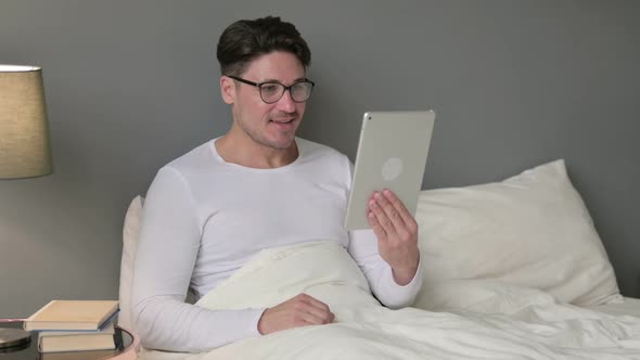 Online Video Chat on Tablet By Middle Aged Man in Bed