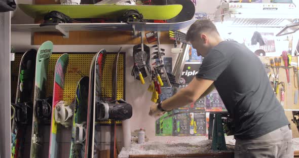 Repairman Is Scraping Wax Off. Snowboard Maintenance And Repair Concept.