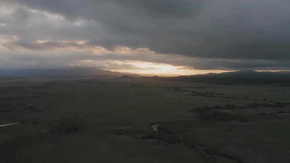 Drone View of a Sunset in a Valley with a River and Mountain Ranges