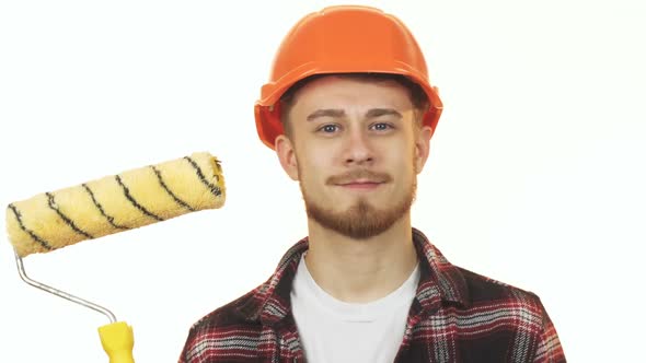 Happy Young Male Builder Holding Paint Roller Showing Thumbs Up