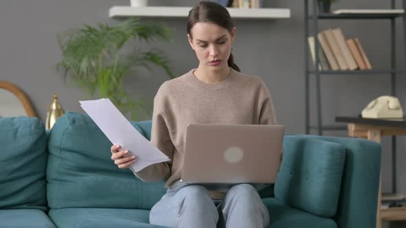 Woman with Laptop Working on Documents on Sofa