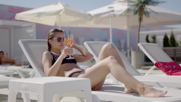 Front View of a Beautiful Woman Drinking a Cocktail While Relaxing on a Sun Lounger
