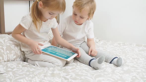Sweet Caucasian Children Use Modern Gadget Holding Tablet in Hands