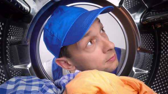 Master repairman looks inside washing machine, smells stench and plugs his nose