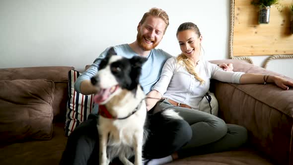 Beautiful Couple Relaxing at Home and Loving Their Dog