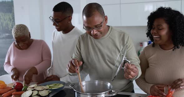 Happy latin family having fun cooking together inside kitchen at home