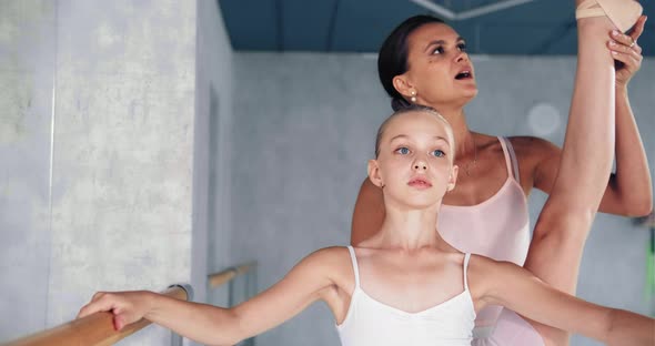 Woman Helps Preteen Girl Do Raise Up Leg Leaning on Barre