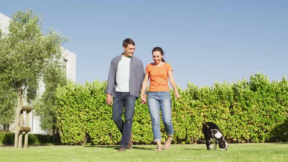 Happy caucasian couple is taking their dog for a walk