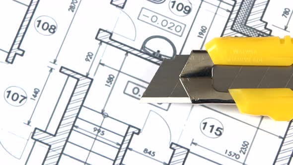 Yellow Stationery Knife on Building Plan, Rotation, Close Up