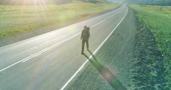 Flight Over Hitchhiker Tourist Walking on Asphalt Road