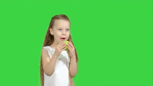 Portrait of a Little Girl Eating Green Apple on a Green Screen, Chroma Key