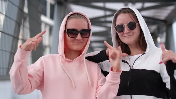 Two fashionably dressed girls dance in the middle of the street. Cool dance of two girlfriends.