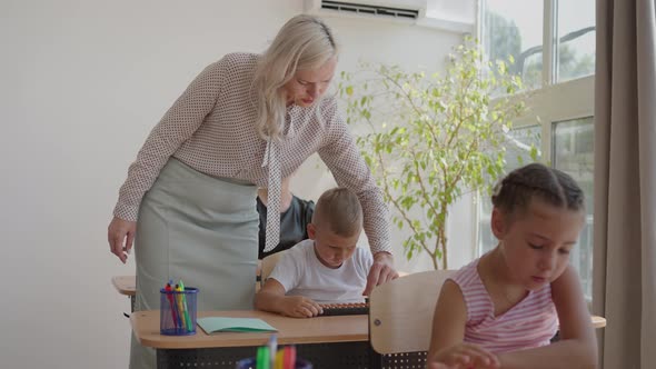 In Elementary School Class Enthusiastic Teacher Walks Between Rows of Bright Diverse Children