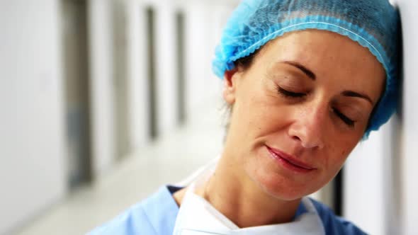 Sad surgeon leaning on wall in corridor