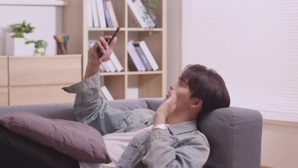 Asian man making facetime video calling with smartphone at home.