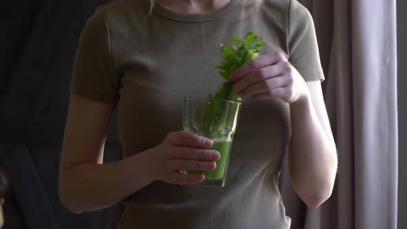 woman with celery juice in a glass at home