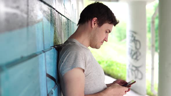 Street Portrait of a Man in Everyday Clothes. The Man Uses the Phone. A Person Dials a Message