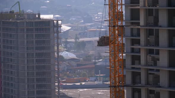 Tower Crane on a Construction Site Lifts a Load at High-rise Building.