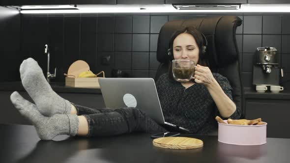 Girl in headphones listening to music and working on laptop computer at home