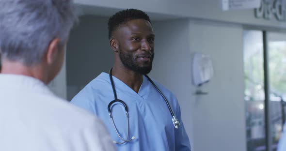 Smiling african american male doctor discussing with diverse colleagues at a hospital staff meeting