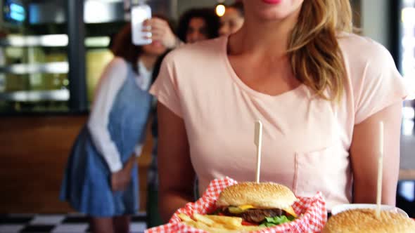 Happy waitress holding tray of food in restaurant