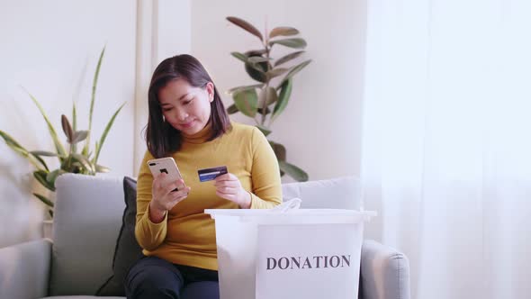 Woman pressing phone using a credit card to pay online to reserve donation box delivery.