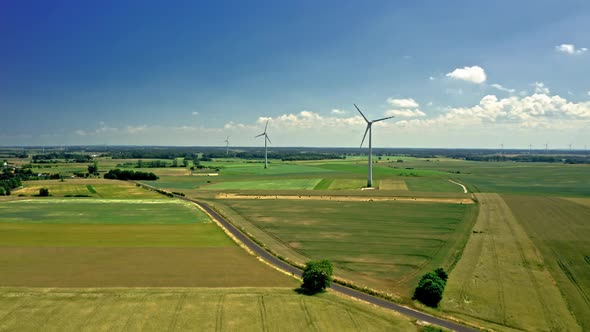 Aerial view of wind turbine on green field during harvest alt