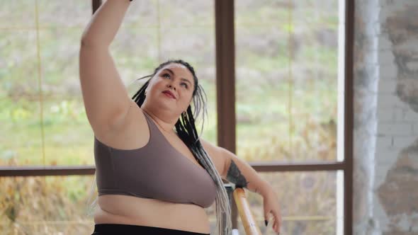 Happy Body Positive Fat Woman with Dreadlocks Doing Stretching Legs in the Gym