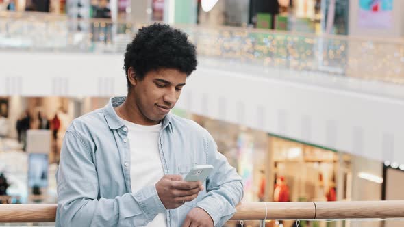 African 20s Man Multiracial Guy Male Standing Indoors Looking at Phone Using Mobile App Social Media